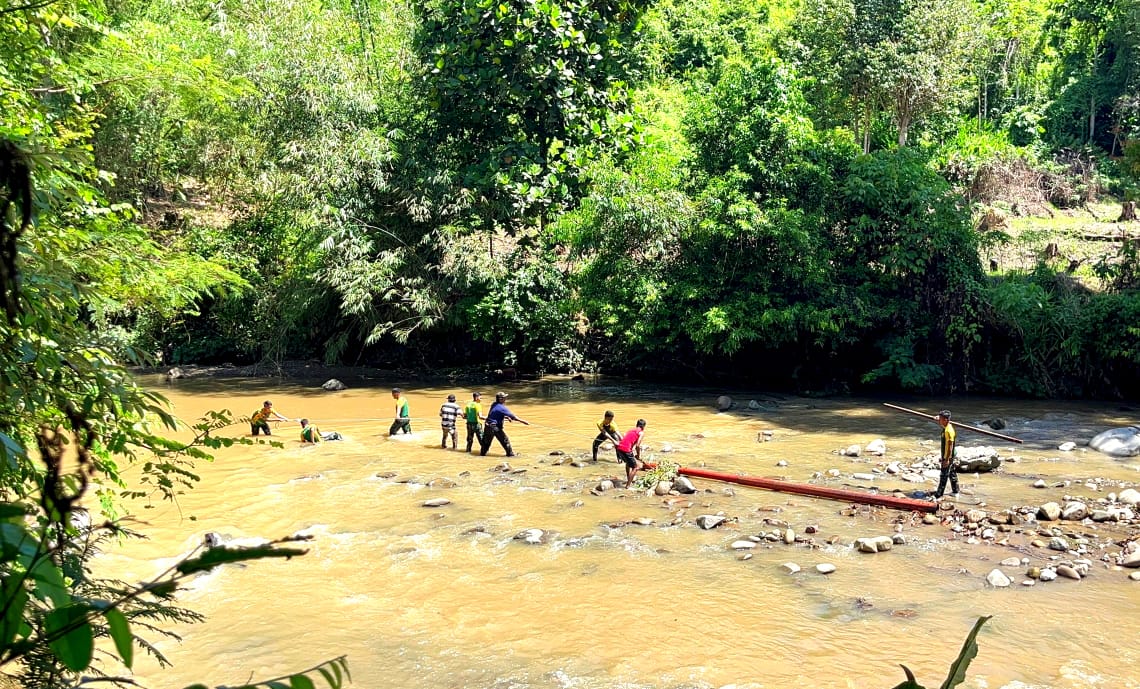 Prajurit Satgas Pamtas Yonarmed 11 Kostrad melaksanakan karya bakti pemindahan tiang listrik melalui jalur sungai di Kecamatan Lumbis Hulu, Sabtu (26/10/2024). (foto: Peneleven/Narwan)