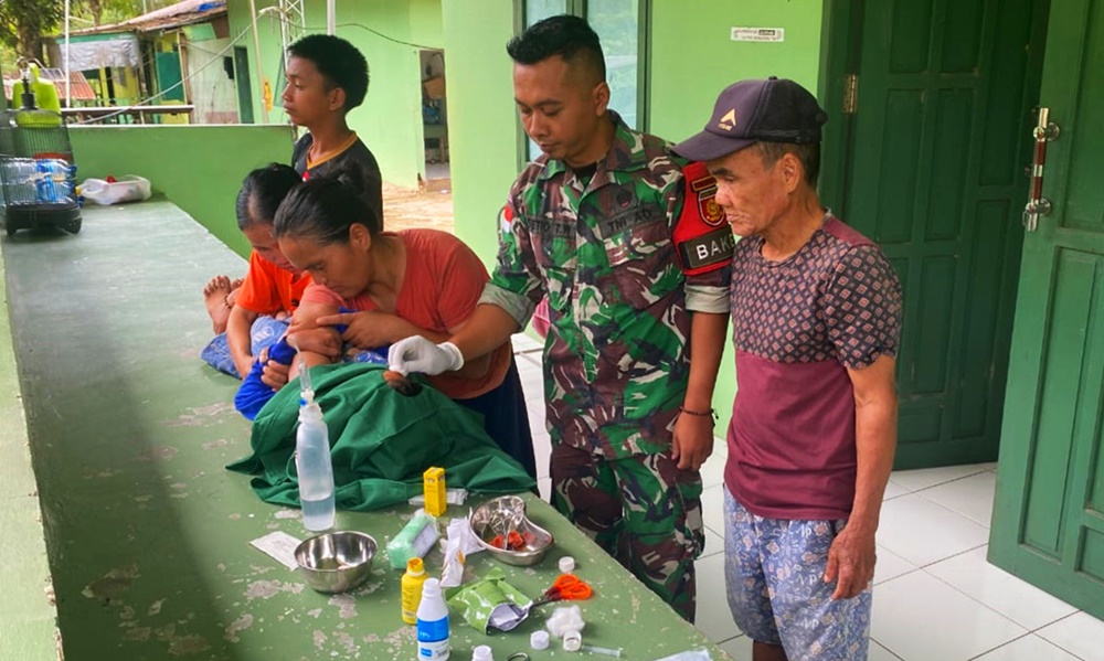 Personel Satgas Pengamanan Perbatasan RI-Malaysia dari Yonarmed 11 Kostrad di Pos Labang memberikan pertolongan medis kepada seorang anak yang mengeluh pada luka jahitan di dahinya, Kamis (28/11/2024). (foto: Peneleven/Narwan)